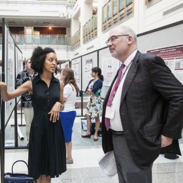 Researcher presenting a poster at a symposium to John M. Cunningham, MD