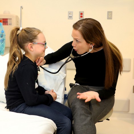 Jaimee Holbrook, MD, checking a patient with a stethoscope 