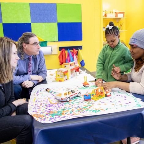 Doctors talking to a mother as her child plays with toys on the table